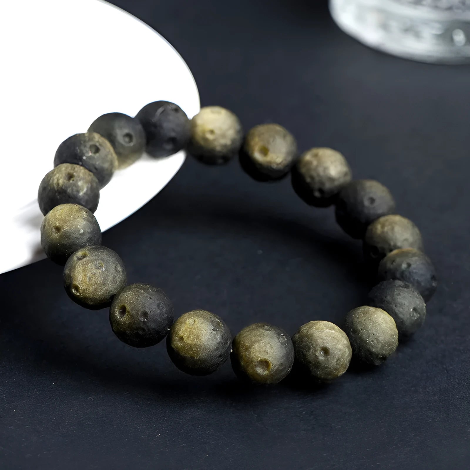 Close-up of an obsidian crater ball bead bracelet showing textured surface from grinding treatment, in silver stone meteorite finish.