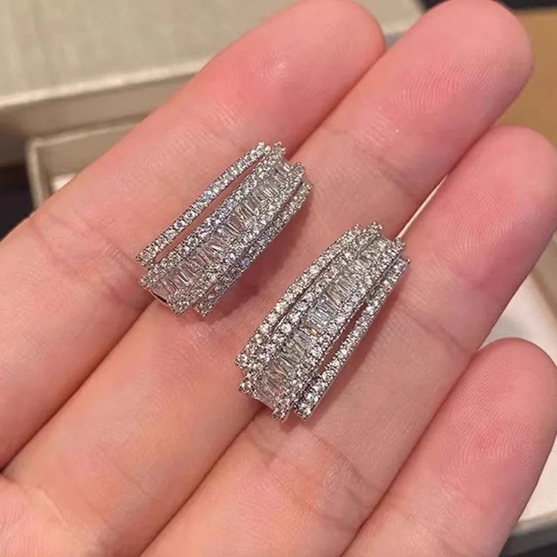 A pair of women's geometric stud earrings with inlaid zircon detail in a white gold colour.