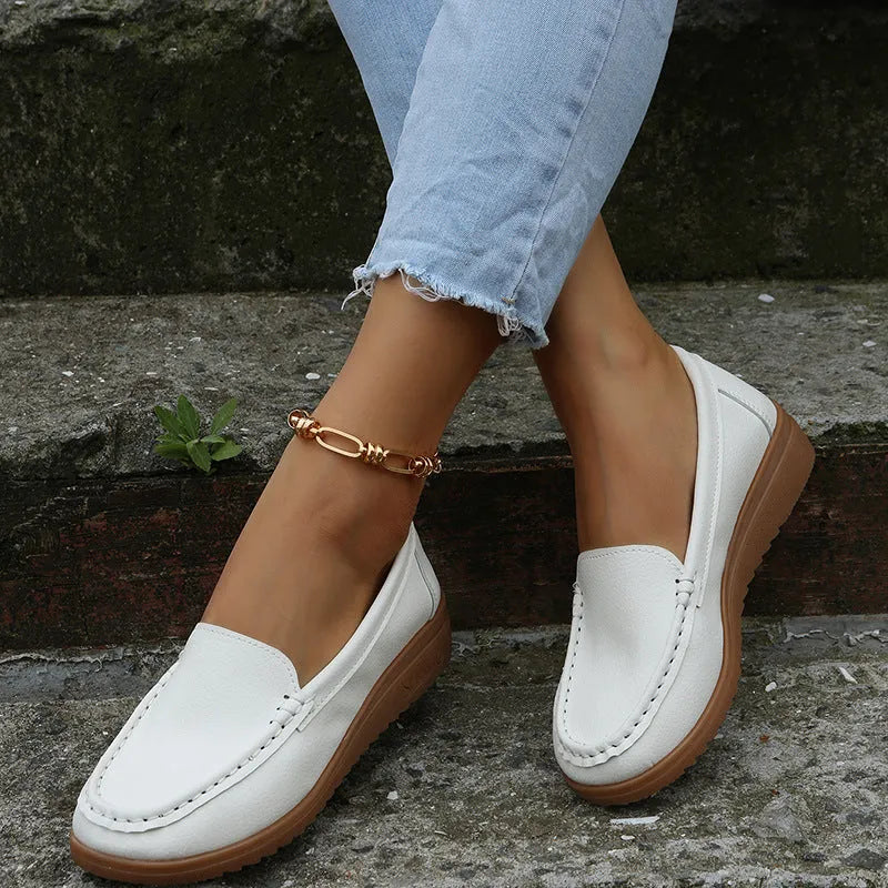 Women's flat loafers in PU leather showing round toe, car suture detail, and a flat rubber sole.