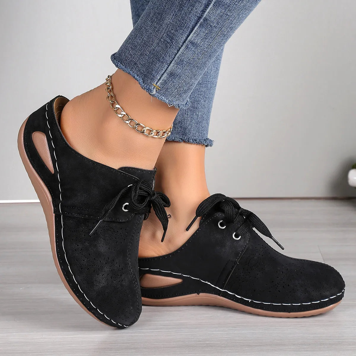 Women's black lace-up wedge slippers with a suede upper and hollow-out rubber sole on a light background.
