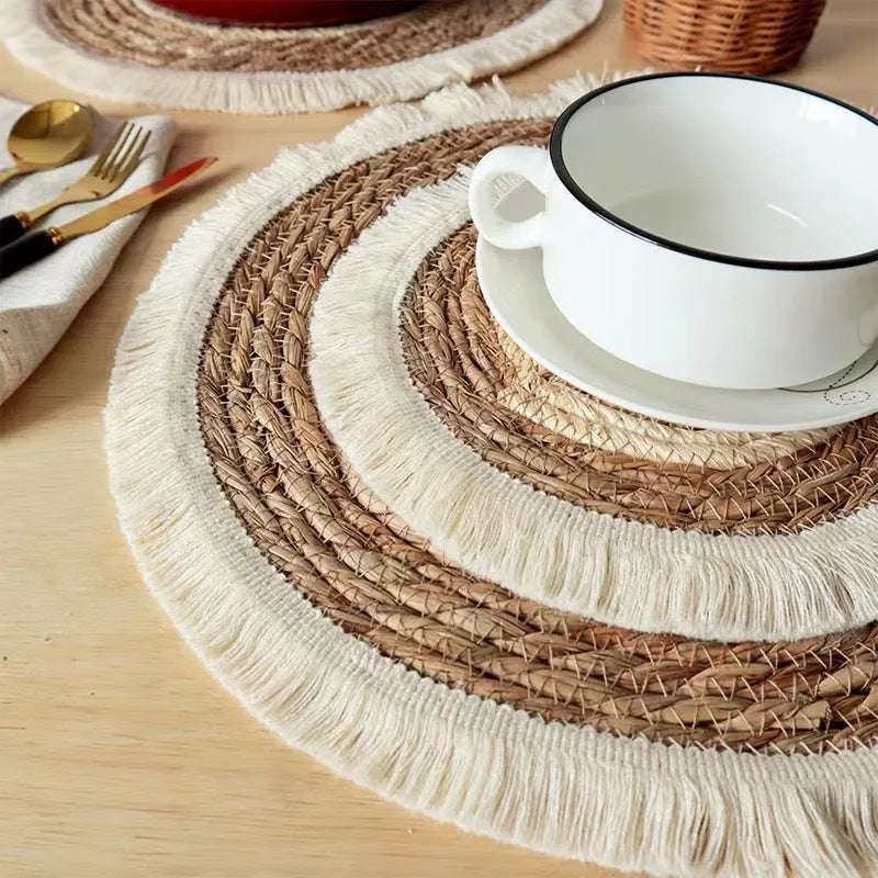 Round papyrus straw placemat with tassel edge in neutral colour on dining table