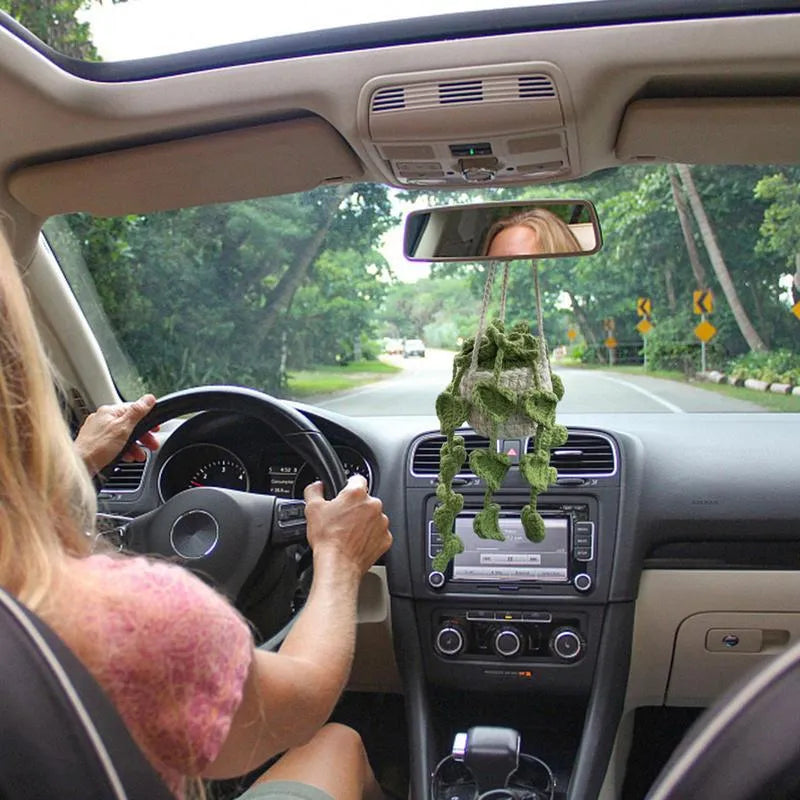 Green and white knitted car plant decoration with hanging rope on car dashboard