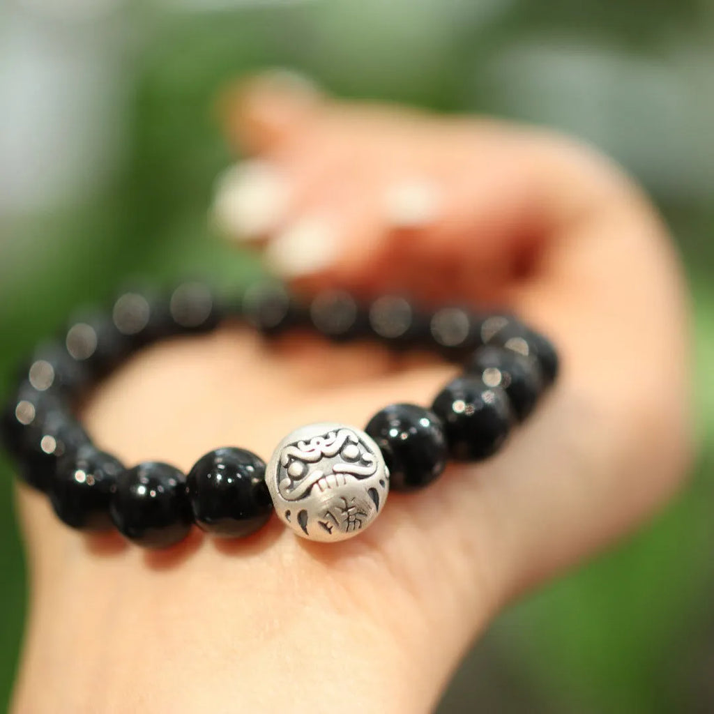 Close-up of a black agate bead bracelet with a sterling silver clasp on a wrist.