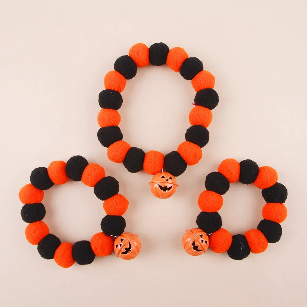 Orange Halloween cat collar with a pumpkin graphic and metal jingle bell on a black background.