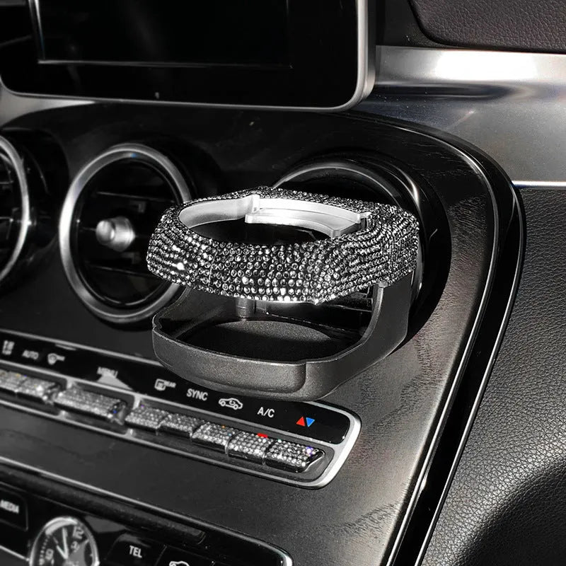 Sparkling rhinestone car cup holder bracket clipped to a vehicle air vent, shown in pink diamond colour.