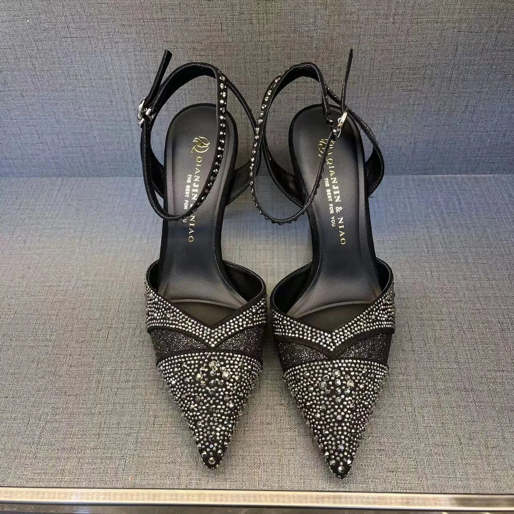 Women's black high heel shoe with stiletto heel, pointed toe, shallow cut, and red sole.
