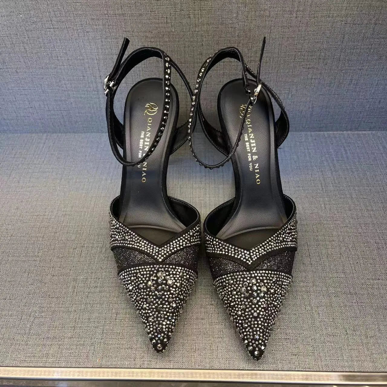 Women's black high heel shoe with stiletto heel, pointed toe, shallow cut, and red sole.