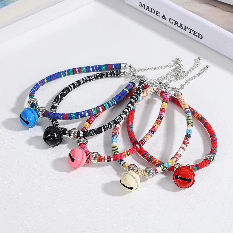 Coloured adjustable pet collar with ethnic embroidery and a metal bell, shown on a dog.