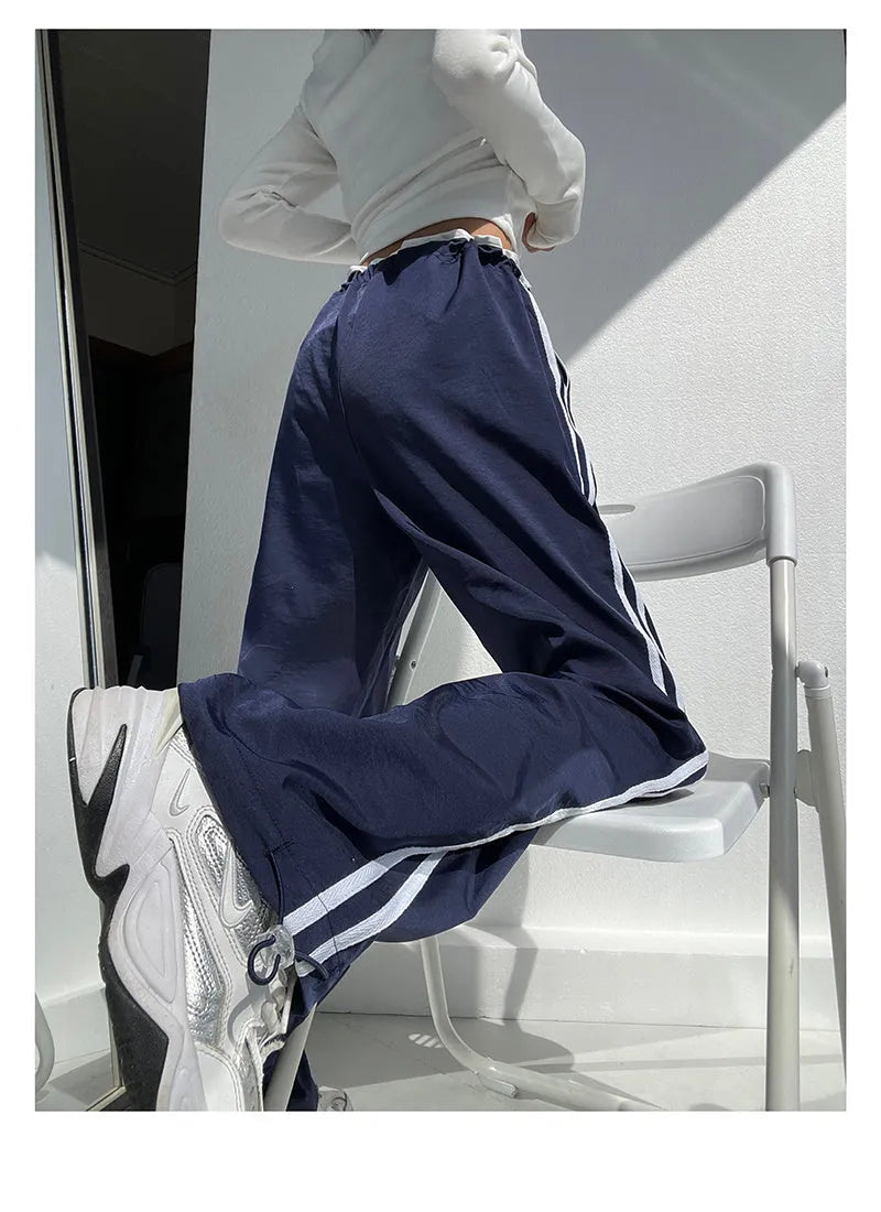 Navy blue loose straight-leg trousers with ribbon-adjustable waist and parallel bars design detail.