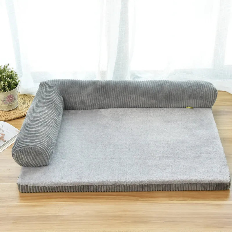 Corduroy dog sofa bed with bolster, shown in grey, placed on a wooden floor.