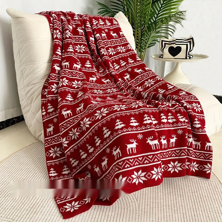 Personalised Christmas blanket with snowflake or reindeer design on a sofa.