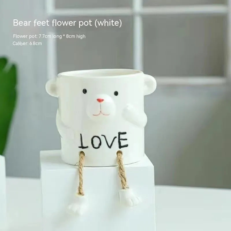 Ceramic cartoon-style succulent flowerpot with hanging foot design on desktop