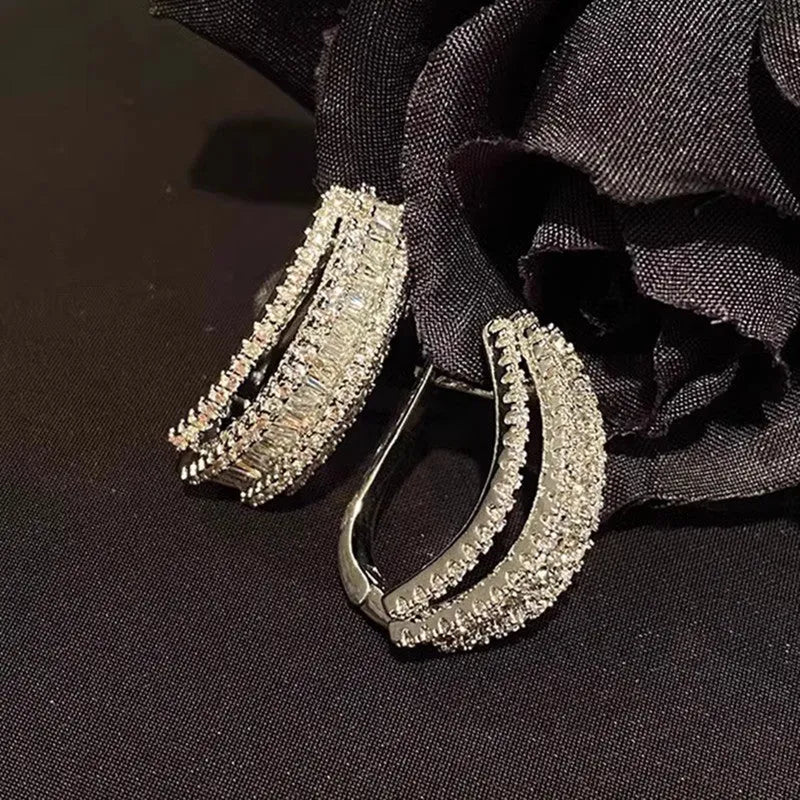 A pair of women's geometric stud earrings with inlaid zircon detail in a white gold colour.