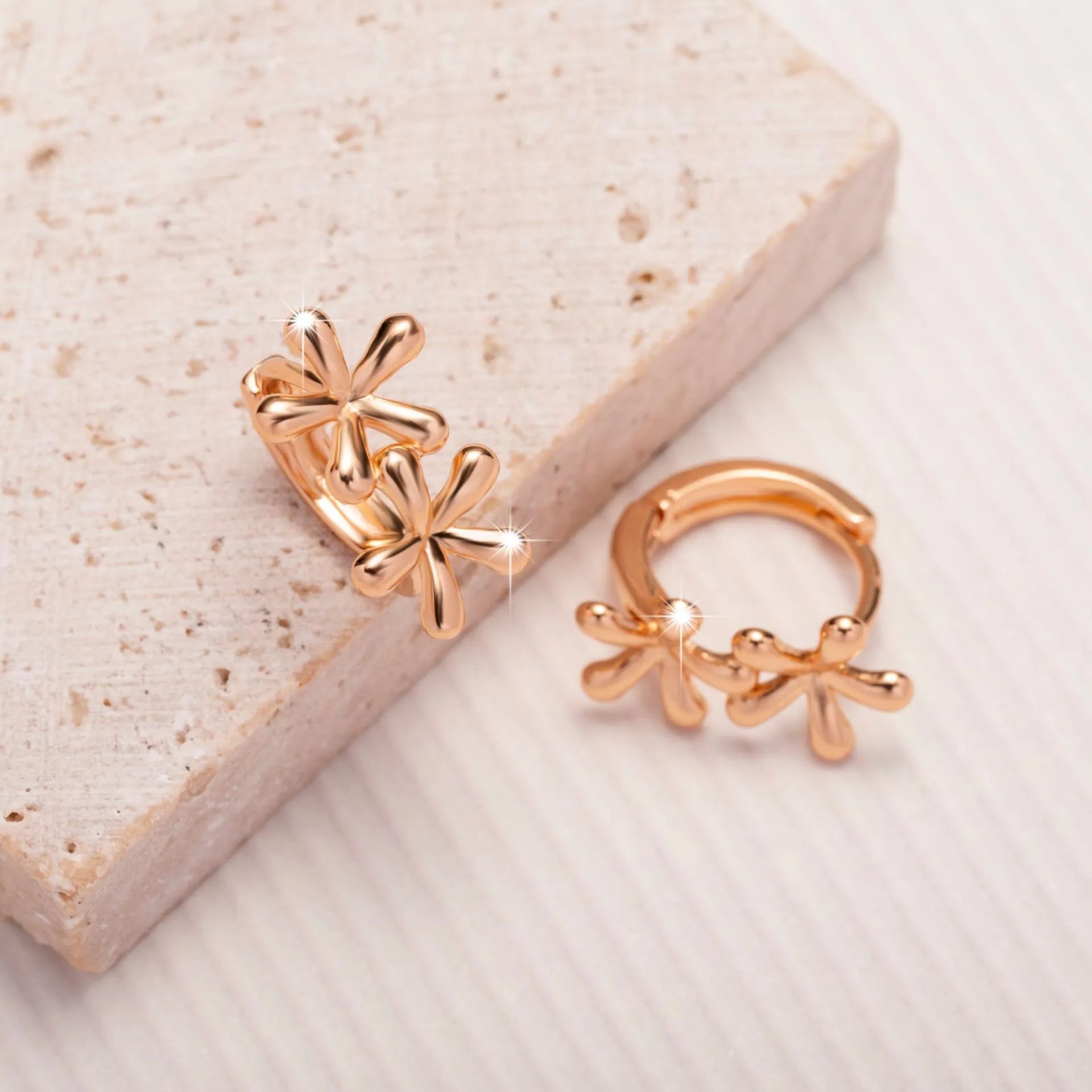 Rose gold coloured circular stud earrings with a detailed waterdrop floral design.