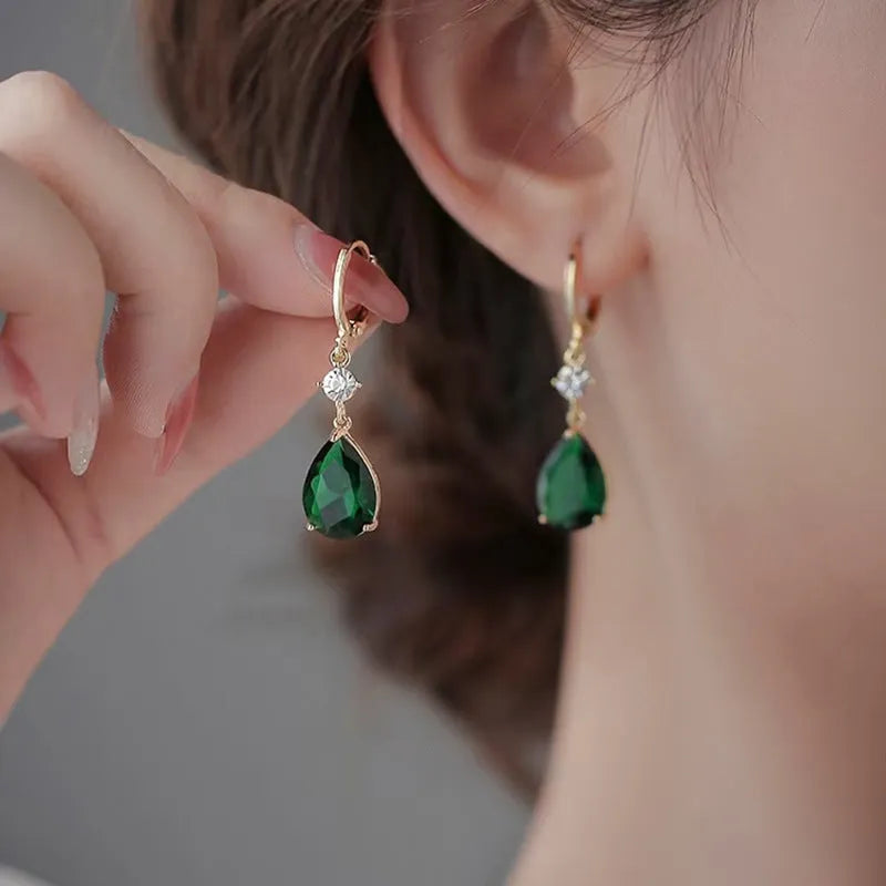 A pair of green geometric teardrop alloy earrings on a plain background.