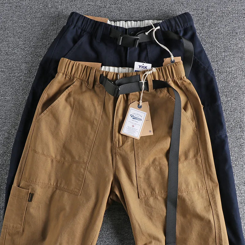 Men's khaki cotton work trousers with mid waist and zipper fly on a neutral background