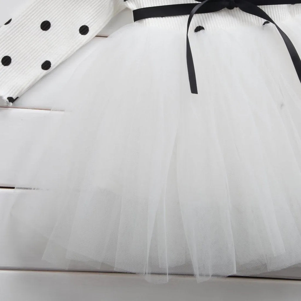 Baby girl wearing a long sleeve white tutu lace dress for a christening or birthday party.