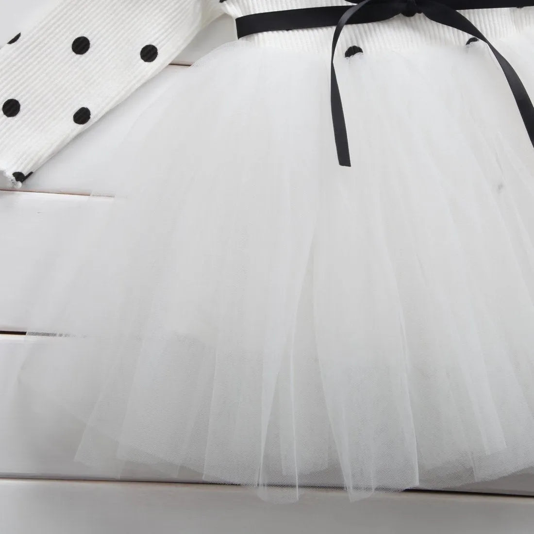 Baby girl wearing a long sleeve white tutu lace dress for a christening or birthday party.