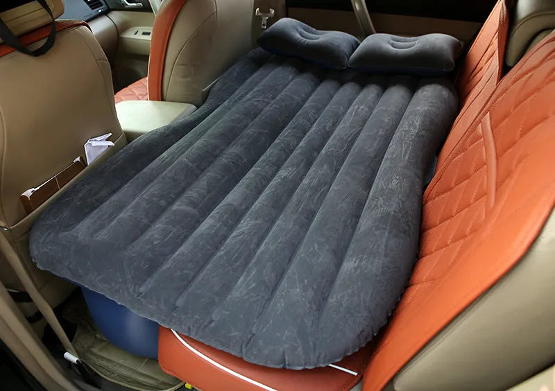 Black inflatable car bed with flocking material and two pillows, shown inside a car.