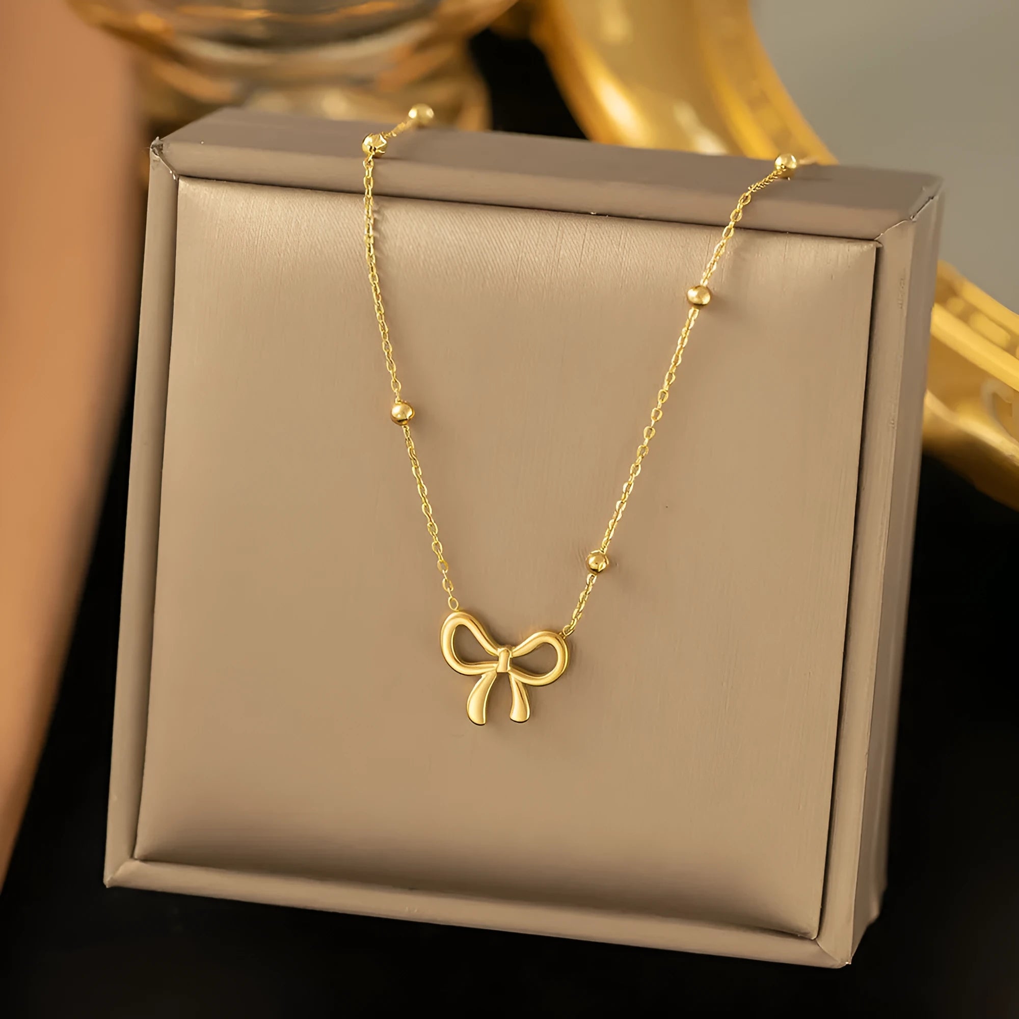 Gold electroplated titanium steel bow necklace with adjustable cross chain