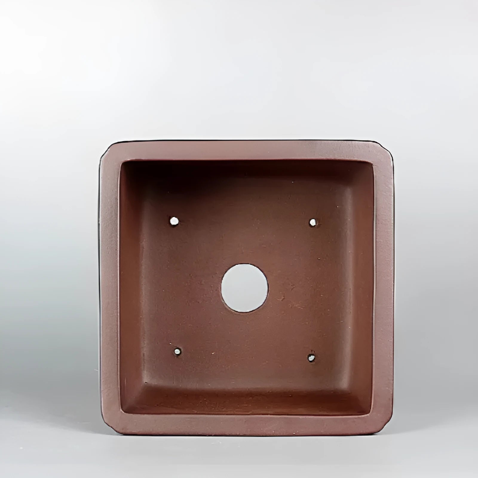 Brown handmade purple clay antique flower pot with single drainage hole.