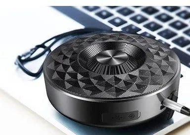 Compact black/orange/silver white portable Bluetooth speaker on a surface, showing its 360-degree grille.