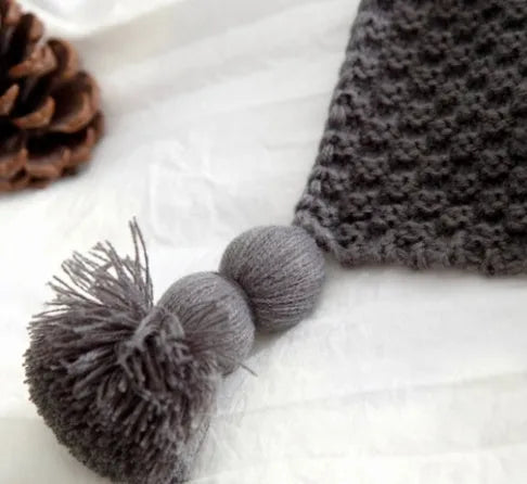 Nordic-style beige acrylic blanket with fringed knit ball detail laid flat.