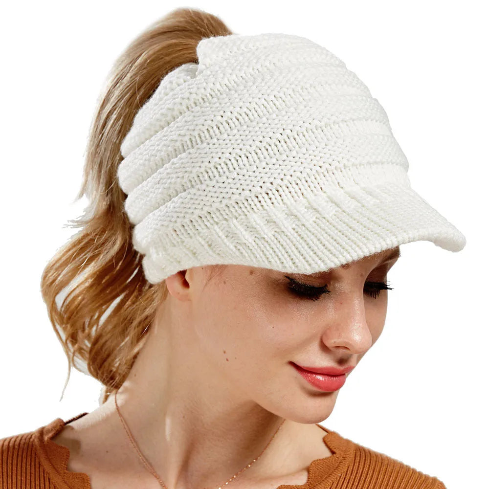 Woman wearing a soft knitted beanie with a ponytail pulled through the opening in the crown.