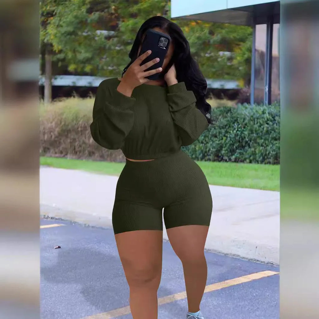 A woman wearing a solid colour off-the-shoulder long-sleeved top and matching shorts from a two-piece set.