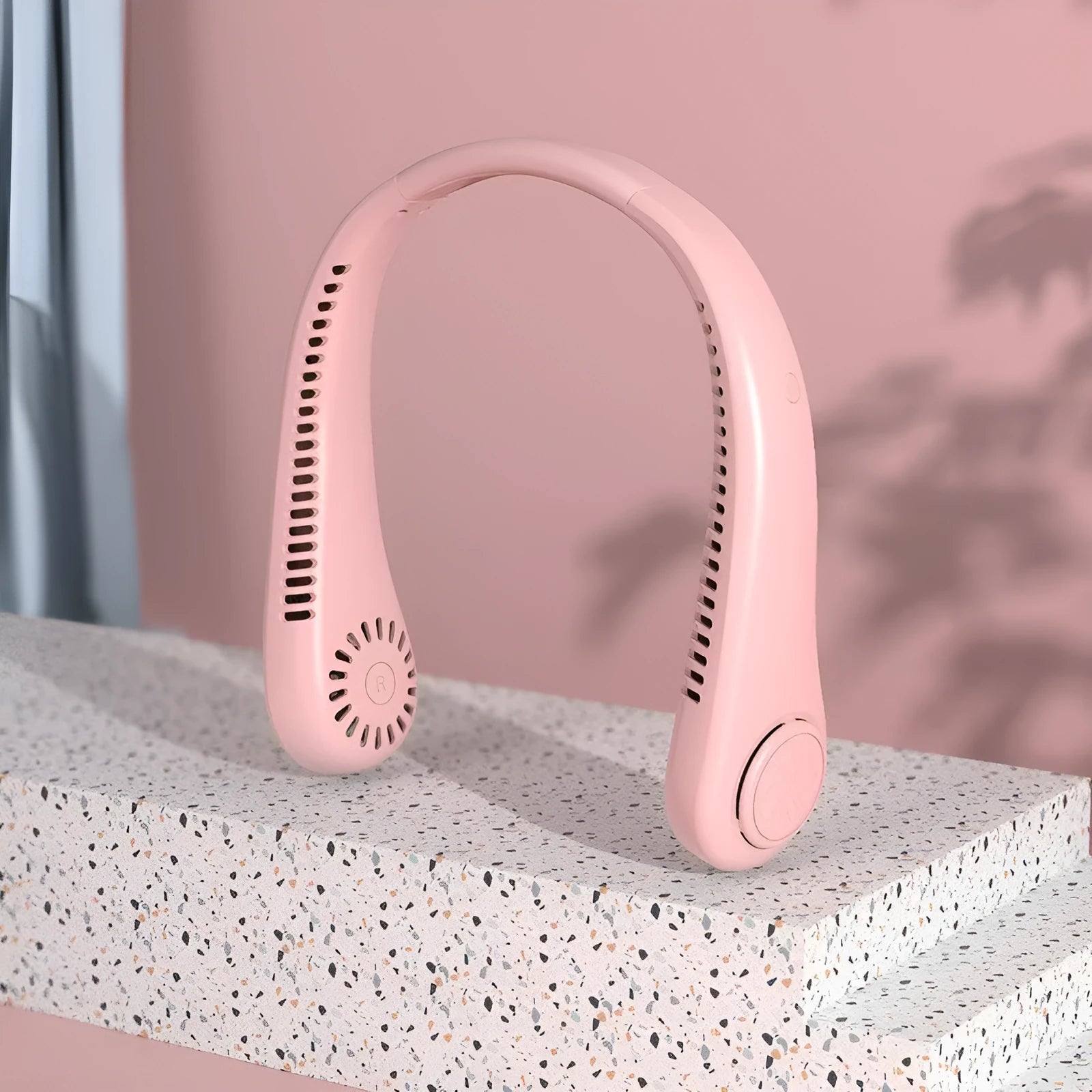 Pink portable bladeless neck fan with flexible neckband and USB charging cable
