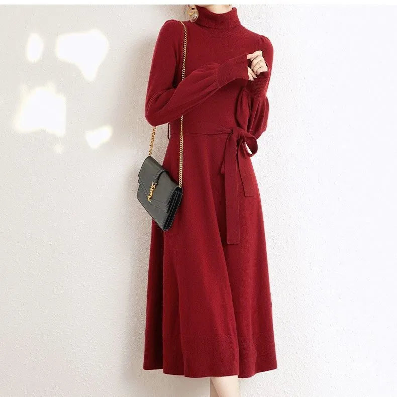 A woman wearing a rose red knitted turtleneck sweater dress with long sleeves, an elastic waist, and a loose, big hem.