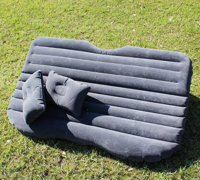 Black inflatable car bed with flocking material and two pillows, shown inside a car.