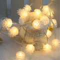 Battery-operated warm white LED string lights with pine cone shaped plastic shells.