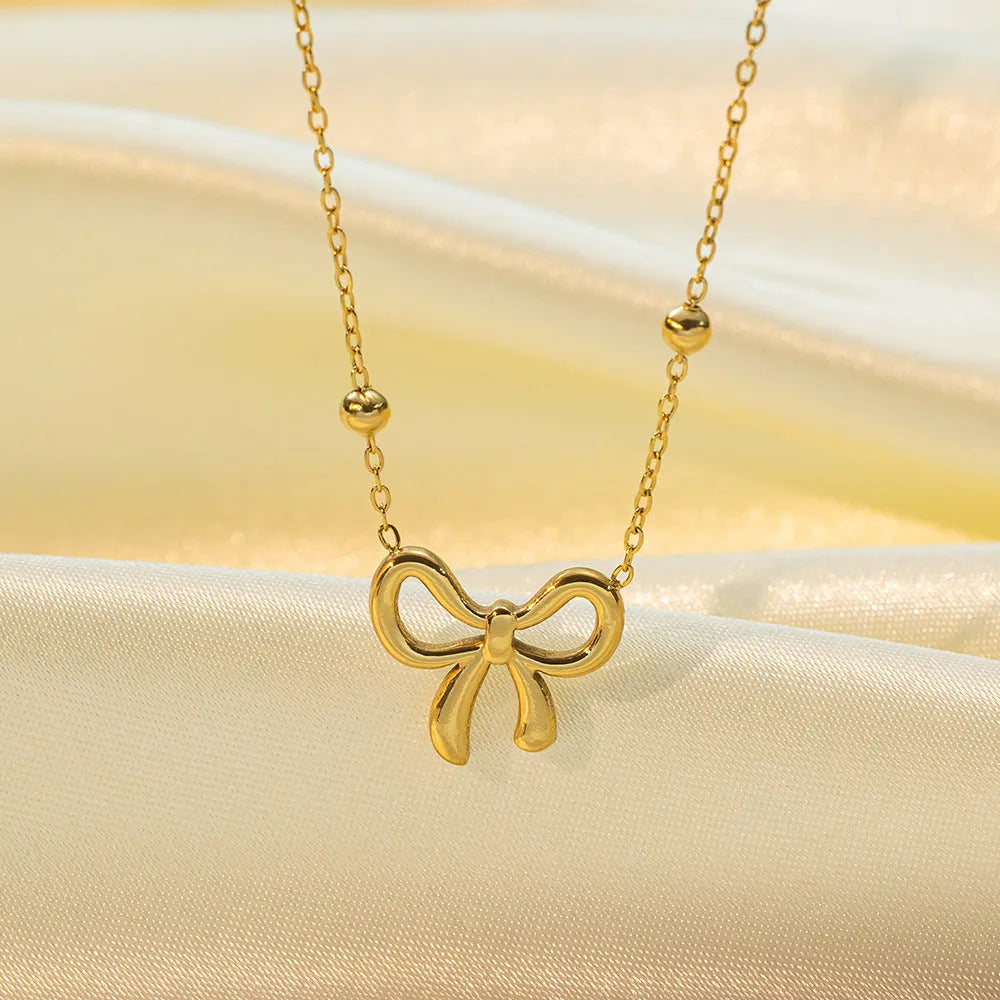 Gold electroplated titanium steel bow necklace with adjustable cross chain