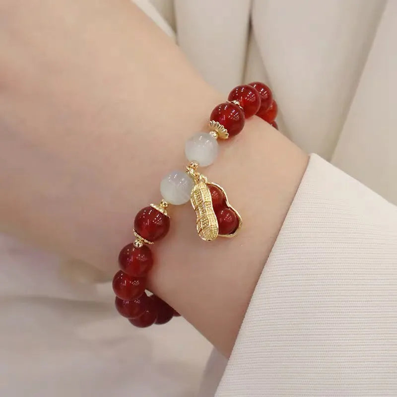 A Chinese style glass bracelet with bamboo leaf and bead designs on a wrist.