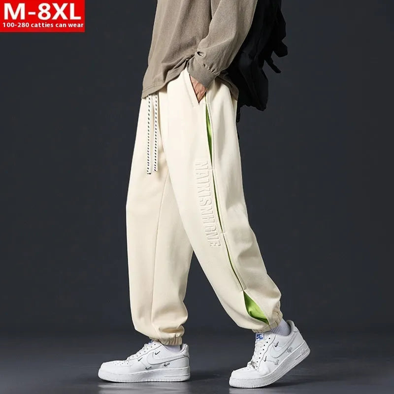 Man wearing loose grey-green cotton trousers with a banded ankle cuff and stitching detail.