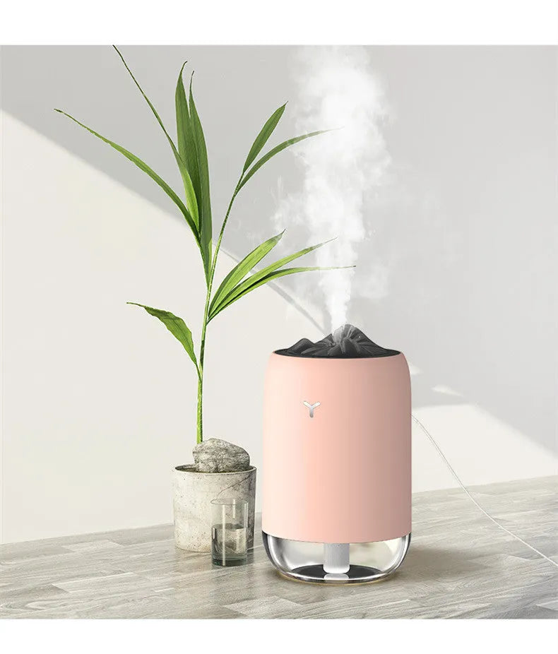 White columnar Magic Flame ultrasonic humidifier with water tank and USB cable on a wooden desk.