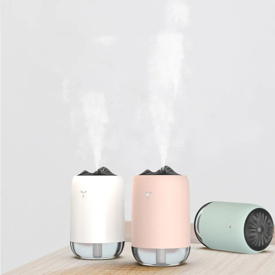 White columnar Magic Flame ultrasonic humidifier with water tank and USB cable on a wooden desk.