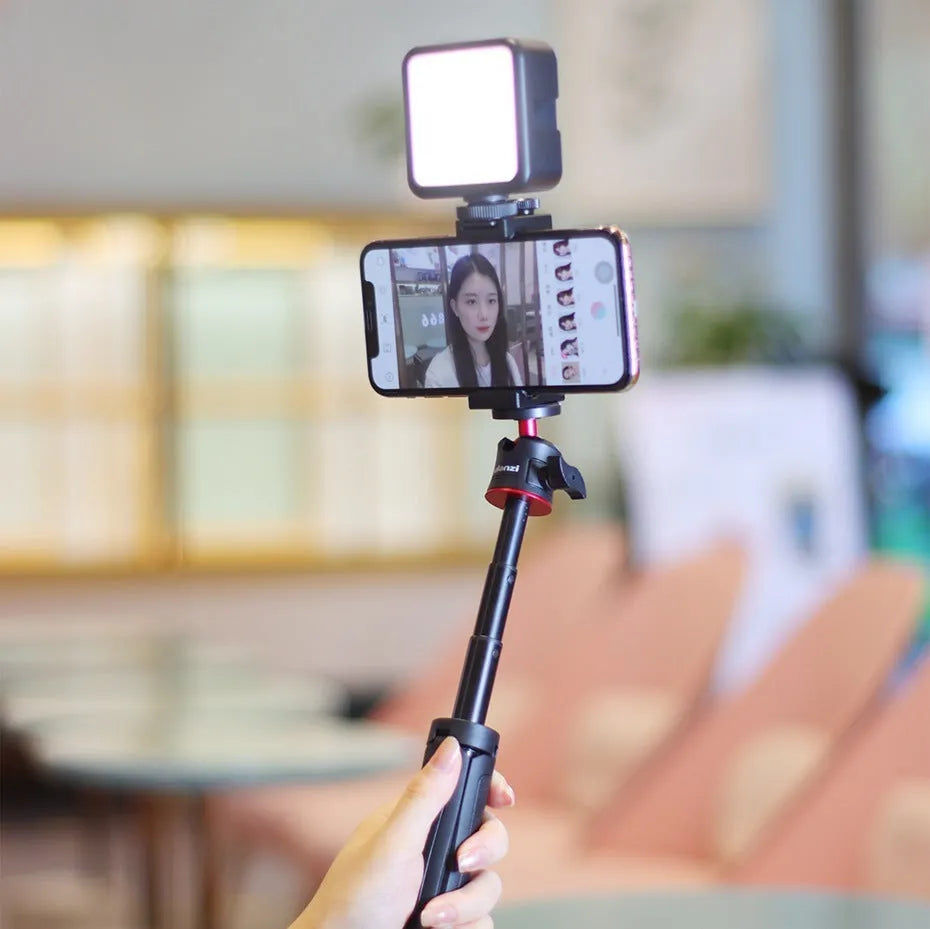 Folded mobile phone vlog bracket with built-in fill light next to a smartphone