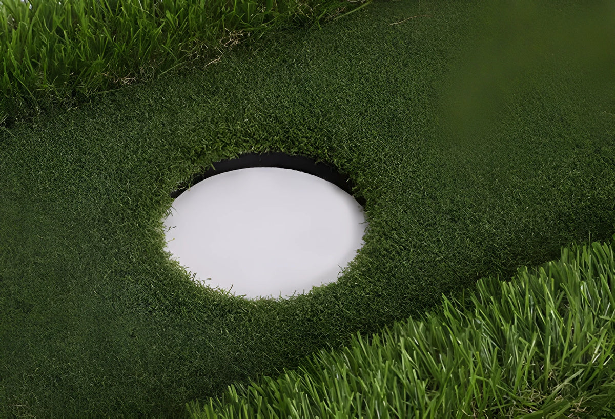 Green golf training mat on a patio, showing PP grass texture and thick EVA foam base edge, with a golf club and ball placed on it.
