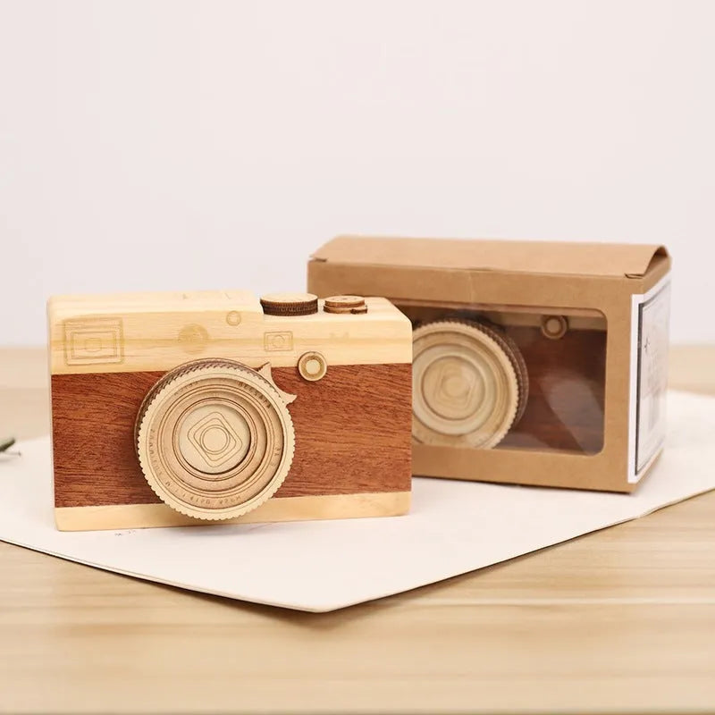 Camera-shaped pine wood music box with rotating sanding box mechanism on a white background.