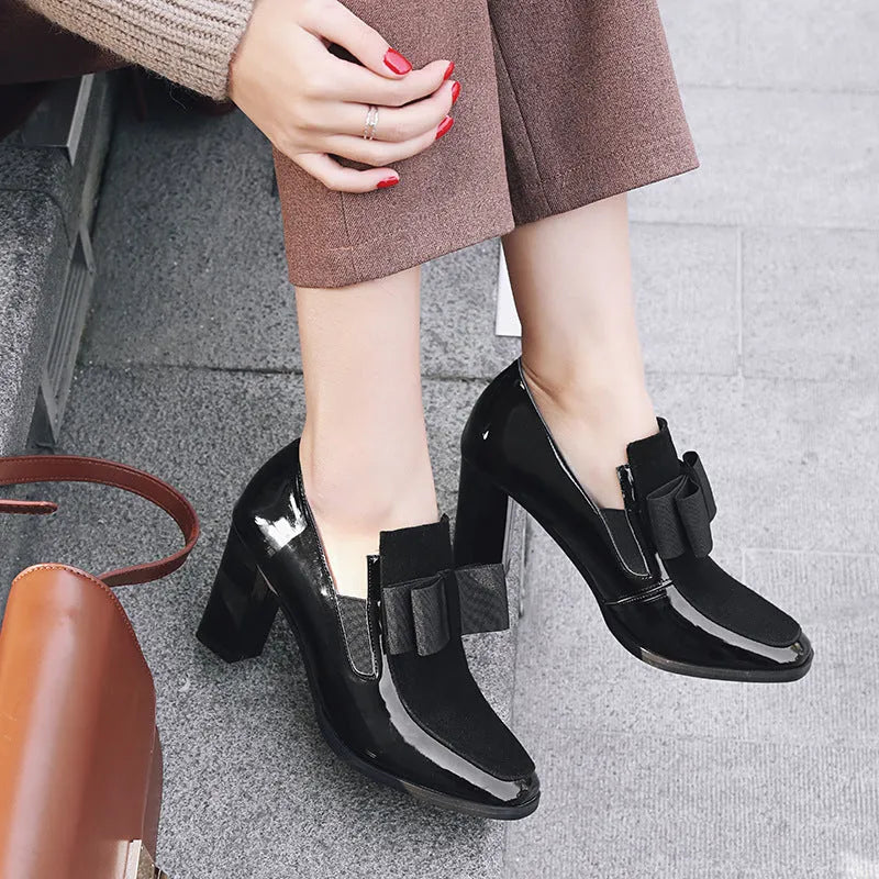 Black patent leather women's high heels with a thick square heel and square toe on a rubber sole.