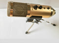 Gold cylindrical condenser microphone on a stand with a USB C cable.