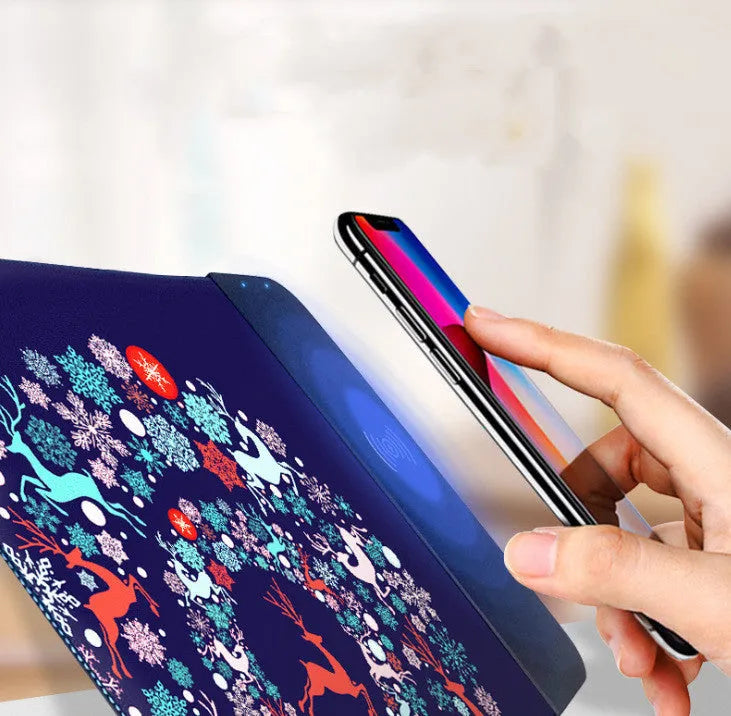 Wireless charging mouse pad with RGB edge lighting and cartoon graphic on black cloth surface.