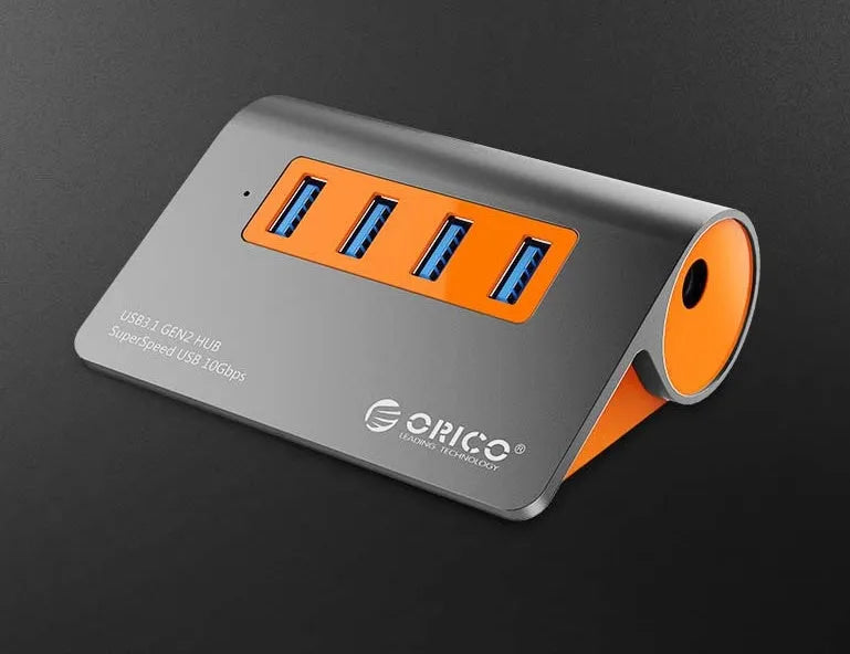Dark grey aluminium USB hub with four orange-trimmed ports and a long black data cable.