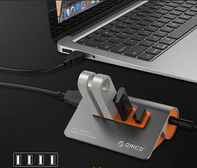 Dark grey aluminium USB hub with four orange-trimmed ports and a long black data cable.