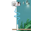 Blue clamp-on mobile phone holder with flexible memory alloy arm attached to a bedside table