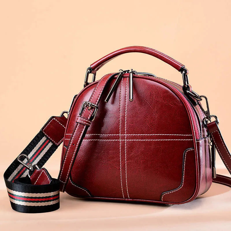 Round leather handbag with zipper closure and soft handle in wine red colour