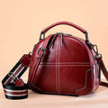 Round leather handbag with zipper closure and soft handle in wine red colour