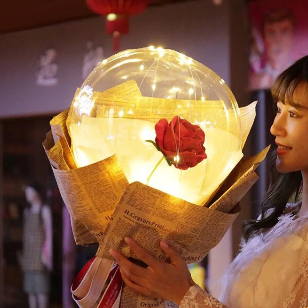 Transparent LED luminous balloon rose bouquet with artificial flowers and integrated lights for party decoration.